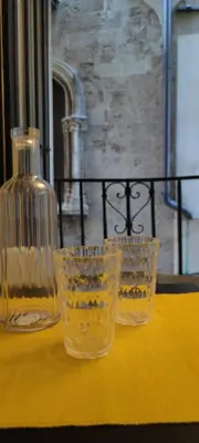 three glasses sitting on a yellow table with a bottle at Le Casette in Palermo