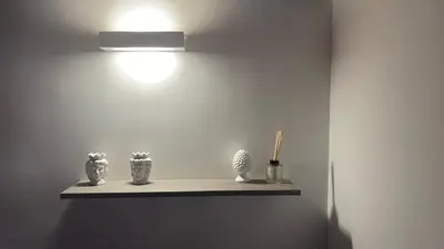 a shelf with three vases on a wall with a light at Domus Conte Federico in Palermo