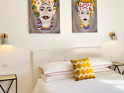 a bedroom with three paintings on the wall above a bed at Villa di Nera Apartments in Palermo
