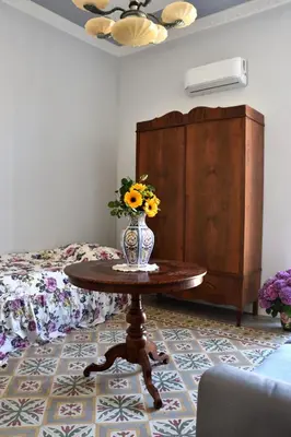 a table with a vase of flowers on it in a bedroom at Battisti 18 Vintage Rooms in Palermo