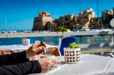 a person sitting at a table with a cup of coffee at Hotel Cala Marina in Castellammare del Golfo