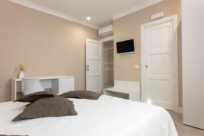 a white bedroom with a white bed with two pillows at Le Palme in Terrasini