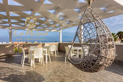 a swing on a patio with a table and chairs at Le Palme in Terrasini