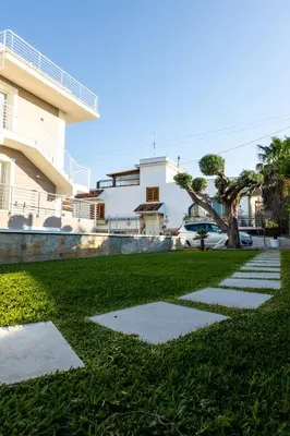 a grassy yard with stepping stones in front of a building at Le Palme in Terrasini