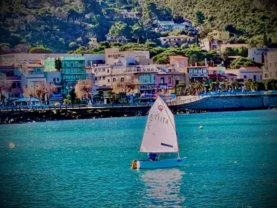 a small sail boat in the water near a city at Appartamento Green Room in Palermo