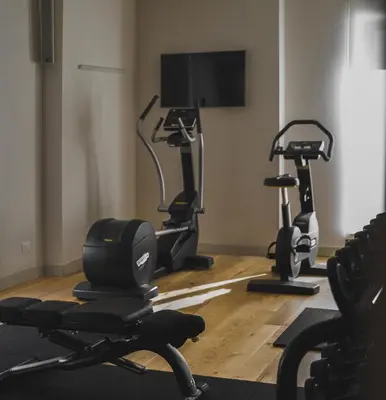 a gym with three exercise bikes and a flat screen tv at Hotel Politeama in Palermo