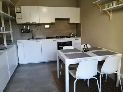 a kitchen with white cabinets and a table and chairs at Appartamento Corallo in San Vito lo Capo