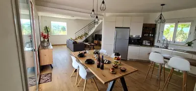 a kitchen and living room with a wooden table and chairs at Villa Arianna, il piacere di vivere nella natura. in Alcamo