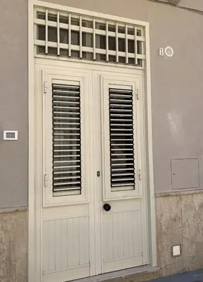 a white door with two windows on a building at Casa Katrin & Casa Brigida in Castellammare del Golfo