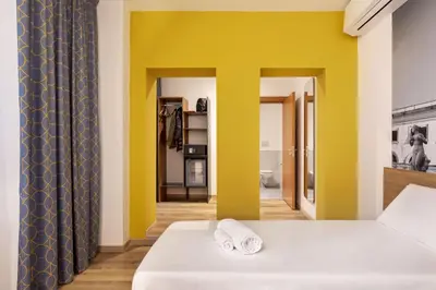 a bedroom with yellow walls and a bed with two towels at B&B Hotel Palermo Quattro Canti in Palermo