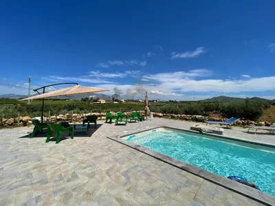 a swimming pool with a table and chairs and an umbrella at Relais del sole in Partinico