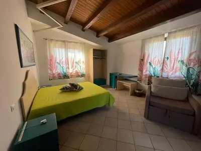 a bedroom with a green bed and a chair and windows at Relais del sole in Partinico