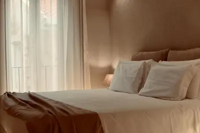 a bed with white sheets and pillows next to a window at Palermo Inn Collection - Boutique Art Hotel in Palermo