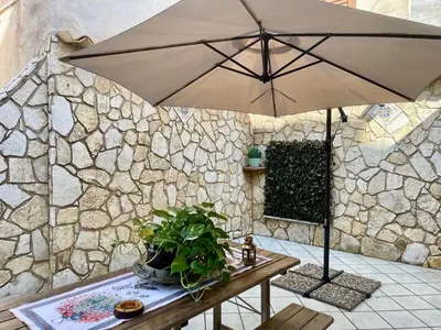 a table with an umbrella next to a stone wall at AMATI HOLIDAYS in Palermo