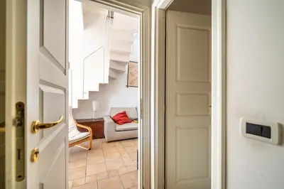 a door leading to a living room with a chair and stairs at Attico nel cuore del centro storico di Palermo in Palermo