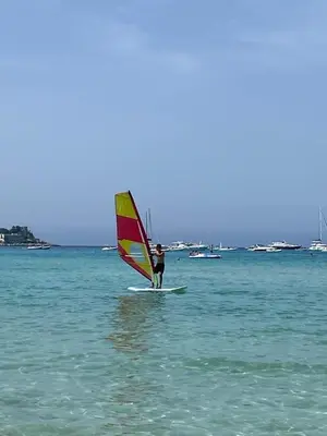 a person on a surfboard with a sail on the water at Belvedere in Palermo