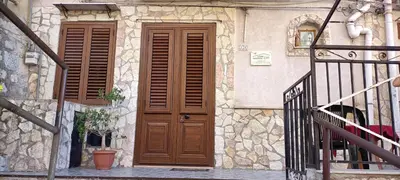 a building with a wooden door and a staircase at Casa di Lia in Montelepre