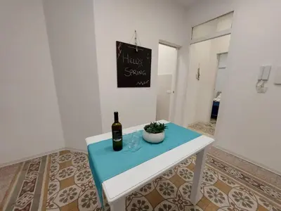 a white table with a bottle of wine and a plant on it at Al cortiletto in Castellammare del Golfo