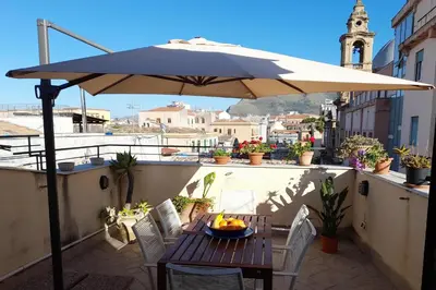 a table and chairs under an umbrella on a balcony at [TERRACE WITH VIEW] Attic in old town BallarHome in Palermo