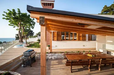 a patio with a wooden table and benches at Villa vista mare con piscina riscaldata a Trappeto in Balestrate