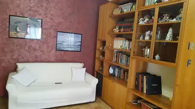 a living room with a white chair and a book shelf at casadifederica in Palermo
