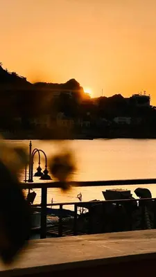 a sunset over a body of water with a table and a boat at La casetta al mare in Palermo