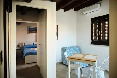 a room with a table and a chair and a bedroom at Mercede Rooms in Palermo