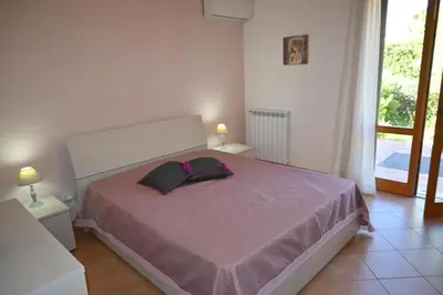 a bedroom with a large bed with a pink blanket at Chalet Calarossa in Terrasini