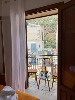 a room with a balcony with a table with a bottle of wine at Appartamento L'Agnuni in Castellammare del Golfo