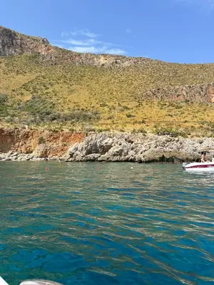 a boat in the water next to a rocky shore at A Petrazzi in Castellammare del Golfo