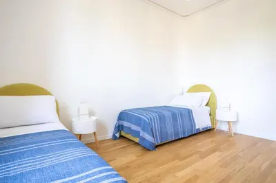 two beds in a room with white walls and wooden floors at Solemar Sicilia - Villa delle Rocce in Bagheria