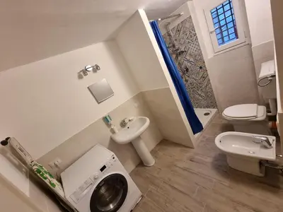 a bathroom with a toilet sink and a washing machine at Domus Sant'Anna Apartment in Palermo