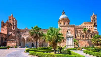 a large building with a clock tower and palm trees at Domus Sant'Anna Apartment in Palermo