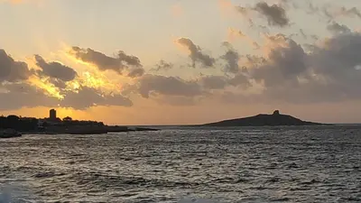 a sunset over the water with a island in the distance at Casa Zibè in Isola delle Femmine