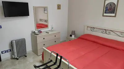 a bedroom with a red bed and a dresser with a mirror at Casa Zibè in Isola delle Femmine