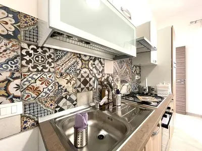 a kitchen with a sink and a tile wall at Casa Pascal in Palermo