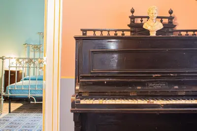 a black piano in a room with a bed at Dimora Lecerf in Palermo