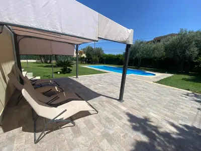 a group of chairs under an umbrella on a patio at Villa del Principe in Carini