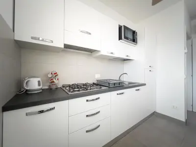 a white kitchen with white cabinets and a stove at Savoia's apartments in San Vito lo Capo