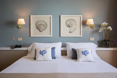 a bedroom with a bed with two pictures on the wall at Hotel Punta Nord Est in Castellammare del Golfo
