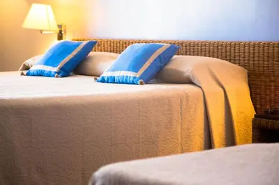 two beds with blue pillows on them in a room at Hotel Cetarium in Castellammare del Golfo