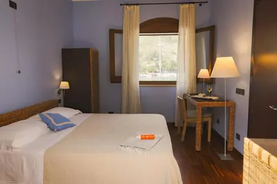 a bedroom with a bed and a desk and a window at Hotel Cetarium in Castellammare del Golfo
