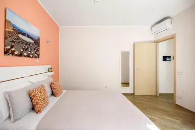 a bedroom with a large white bed with orange walls at Kalatafimi- Palermo Apartment 2 Camere & Wi-Fi in Palermo