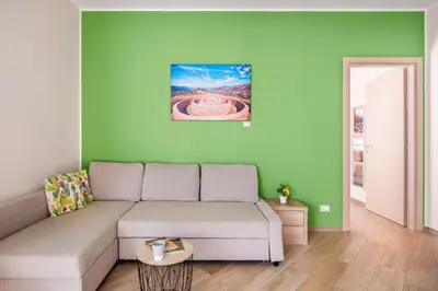 a living room with a couch and a green wall at Kalatafimi- Palermo Apartment 2 Camere & Wi-Fi in Palermo