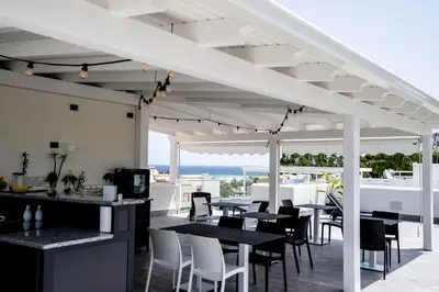 a patio with tables and chairs and a view of the ocean at B&B il Colibrì in San Vito lo Capo