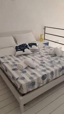 a bed with a blue and white comforter on it at Casa vacanza Raggio di Sole in Castellammare del Golfo