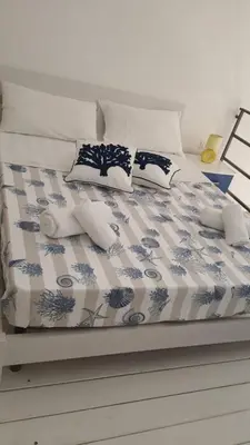 a bed with blue and white sheets and pillows on it at Casa vacanza Raggio di Sole in Castellammare del Golfo