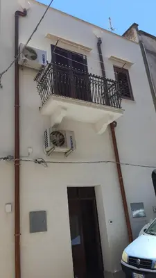 a white building with a balcony and a door at Casa vacanza Raggio di Sole in Castellammare del Golfo