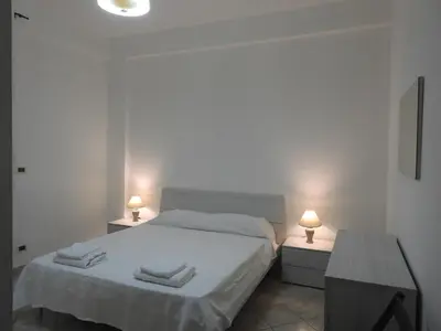 a white bedroom with a bed and two night stands at Leonardo in Capaci