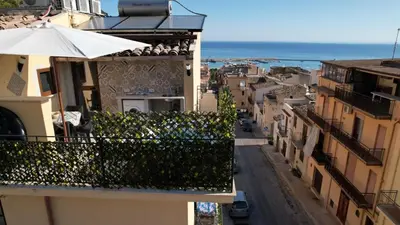 an apartment balcony with an umbrella on a city street at Mary Gery's Rooms in Castellammare del Golfo